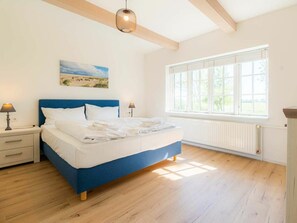 A bedroom with a bed, bedside tables, a window, and a painting on the wall. - Holiday Apartment 3 "norderoog" (Tating)