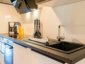 A modern kitchen with a built-in oven, a coffee maker, and a sink. - Holiday Apartment 3 "norderoog" (Tating)