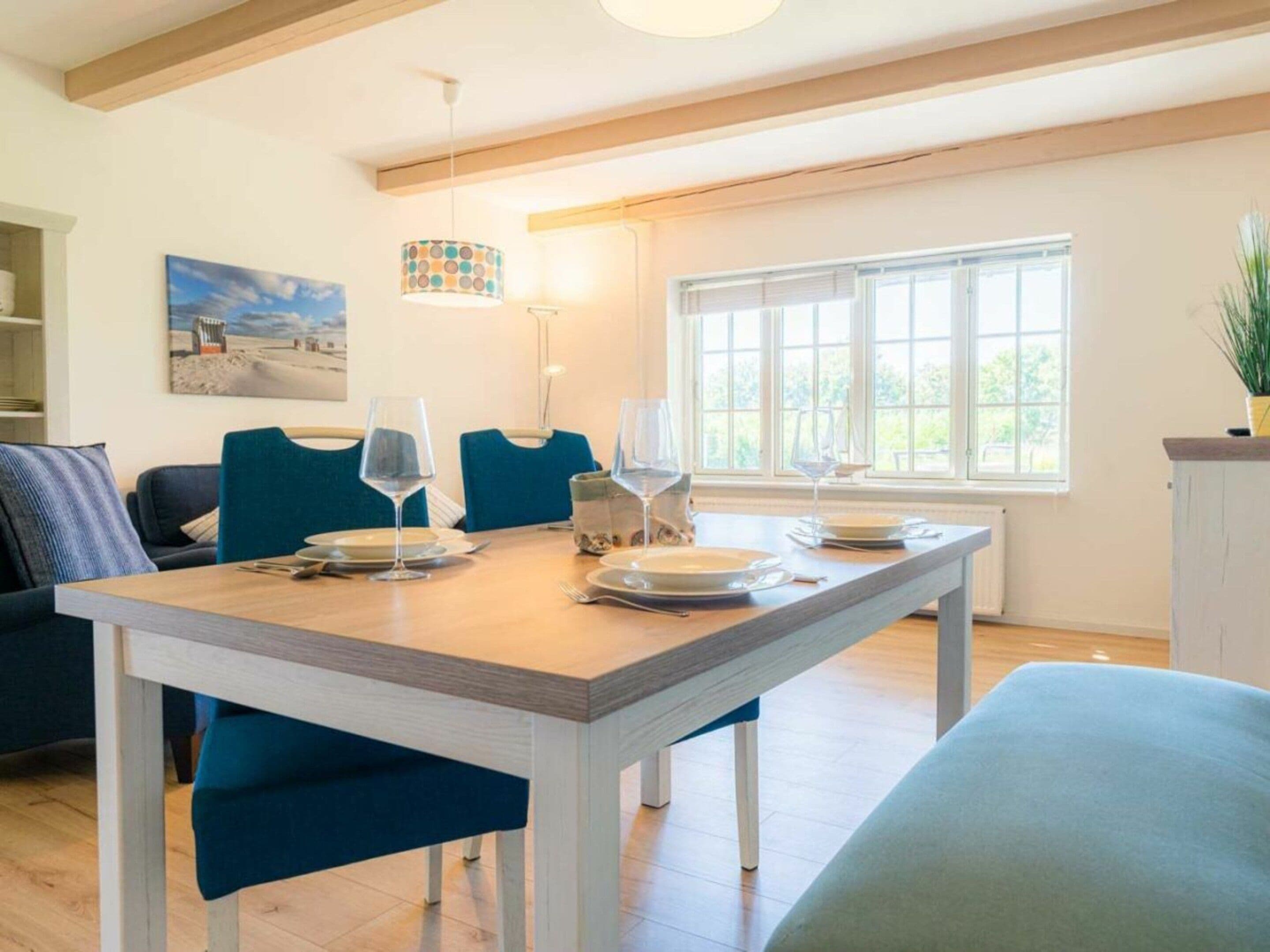 Un comedor con mesa de madera, sillas tapizadas en azul e iluminación colgante.