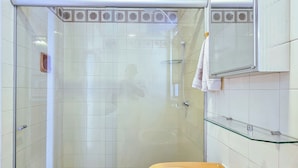 Un baño con cabina de ducha de vidrio, un lavabo amarillo y un espejo sobre él.