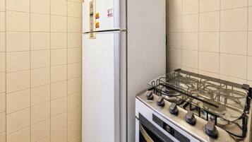 A kitchen with a gas stove and a refrigerator.