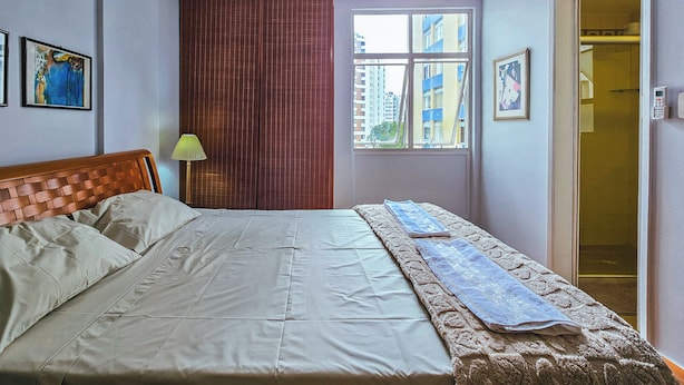 Un dormitorio con cama, ventana, puerta y ventilador de techo.