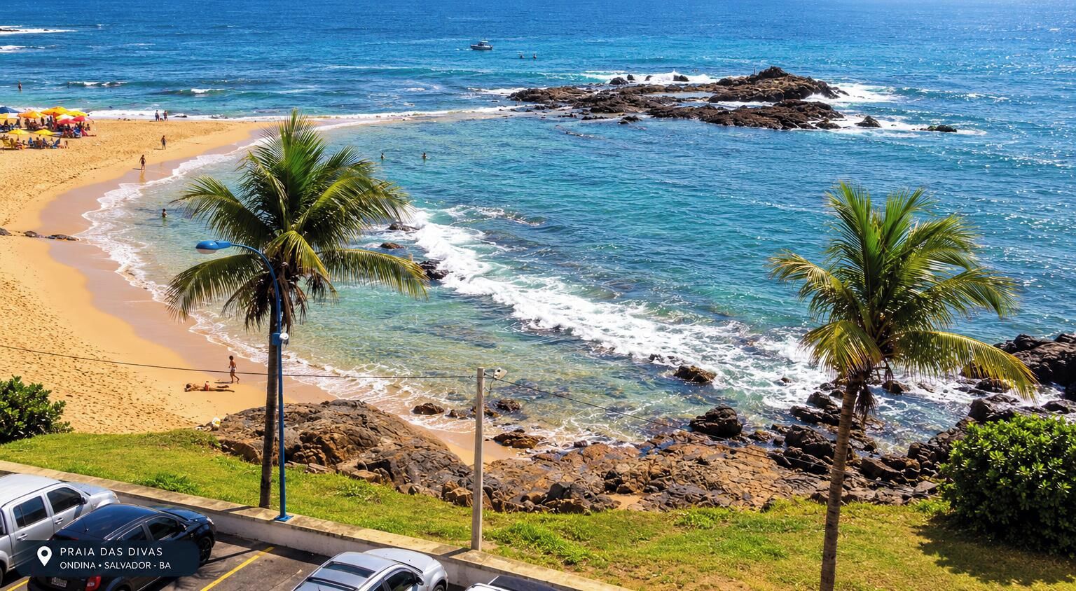 Uma praia com águas azul-claras, palmeiras e formações rochosas.