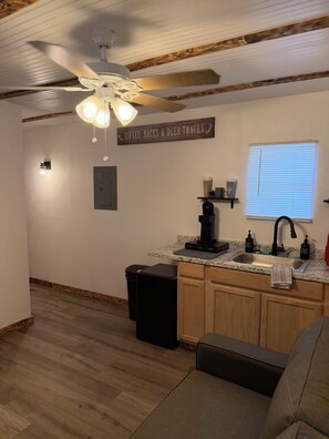 Eine Küche mit Deckenventilator, Kaffeemaschine und einem Schild an der Wand.