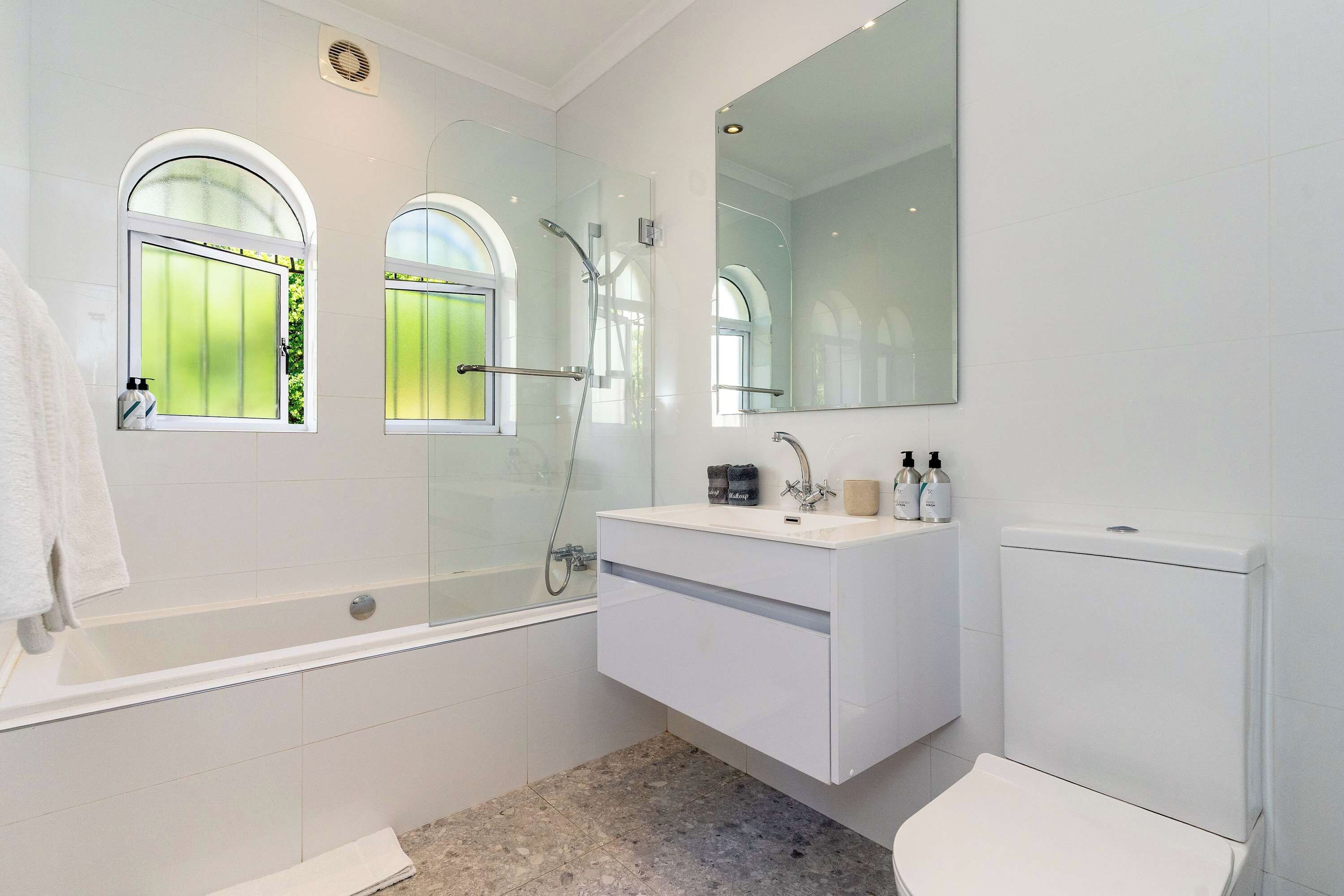 A modern bathroom with a bathtub, a large mirror, and a toilet.