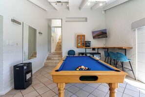 A pool table with balls, a heater, and a TV in a room with white brick walls, a staircase, and blue chairs. - Camps Bay Fam Villa, Pool, Hot Tub - Bella Riposa (Cape Town)