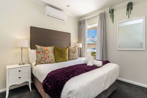 A neatly arranged hotel room with a bed, a nightstand, a lamp, and a window with curtains. - Camps Bay Fam Villa, Pool, Hot Tub - Bella Riposa (Cape Town)