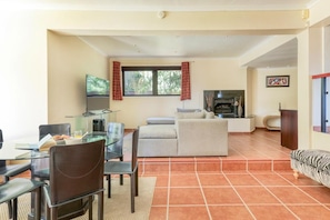 A living room with a sofa, a coffee table, and a TV. There is a fireplace and a window with curtains. - Family Villa, 360 Views, Camps Bay - Villa Sol (Cape Town)