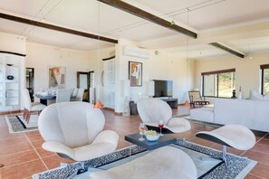 A spacious living room with modern furniture, a flat-screen TV, and a dining area with a table and chairs. - Family Villa, 360 Views, Camps Bay - Villa Sol (Cape Town)