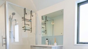 Een badkamer met een douchecabine van glas, een wit toilet en een wastafel met spiegel.