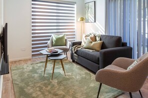 A living room with a sofa, armchair, and a coffee table. - Peaceful 4BR Townhouse - Near Avon River + Garage (Christchurch)