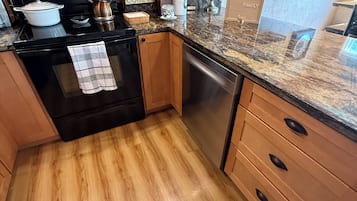 A kitchen with wooden cabinets, a microwave, a stove, and a dishwasher.