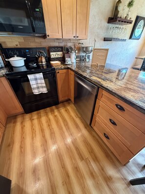 A kitchen with wooden cabinets, a microwave, a stove, and a dishwasher.