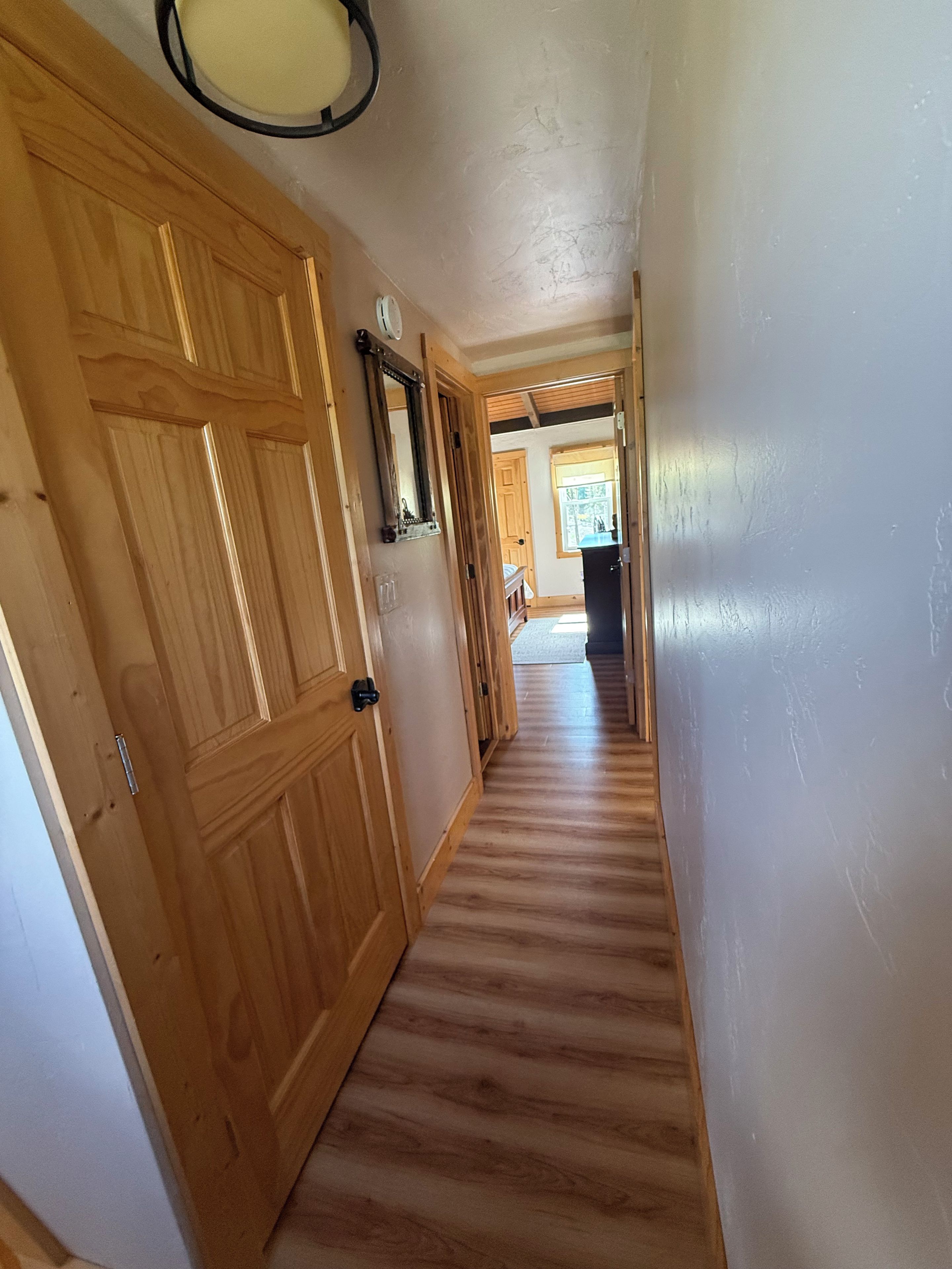 A wooden hallway with a door on the left and a window on the right.
