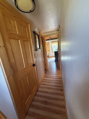 A wooden hallway with a door on the left and a window on the right.