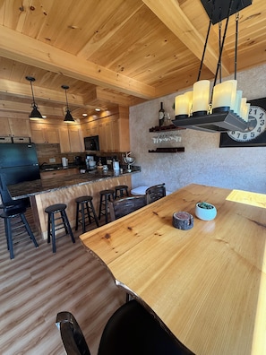 A wooden interior with a kitchen, dining area, and bar stools.