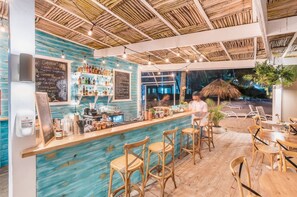 Ein Barbereich im Innenbereich mit Holzbalkendecke, Barhocker und einer Kreidetafel-Speisekarte.