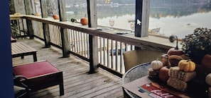 A wooden deck with a railing, a bench, and a table with pumpkins. - Sandy beach, hot tub, amazing sunsets, spacious lake home, kayaks and more. (Wautoma)