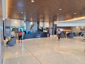 A modern reception area with a marble reception desk, seating area, and a large window. - Shore 1 Residences by LUXE (Pasay City)