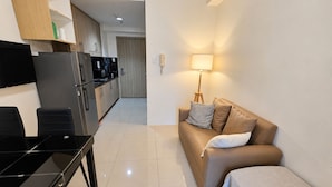 A compact living space with a kitchenette, a dining table, a sofa, and a lamp. - Shore 1 Residences by LUXE (Pasay City)