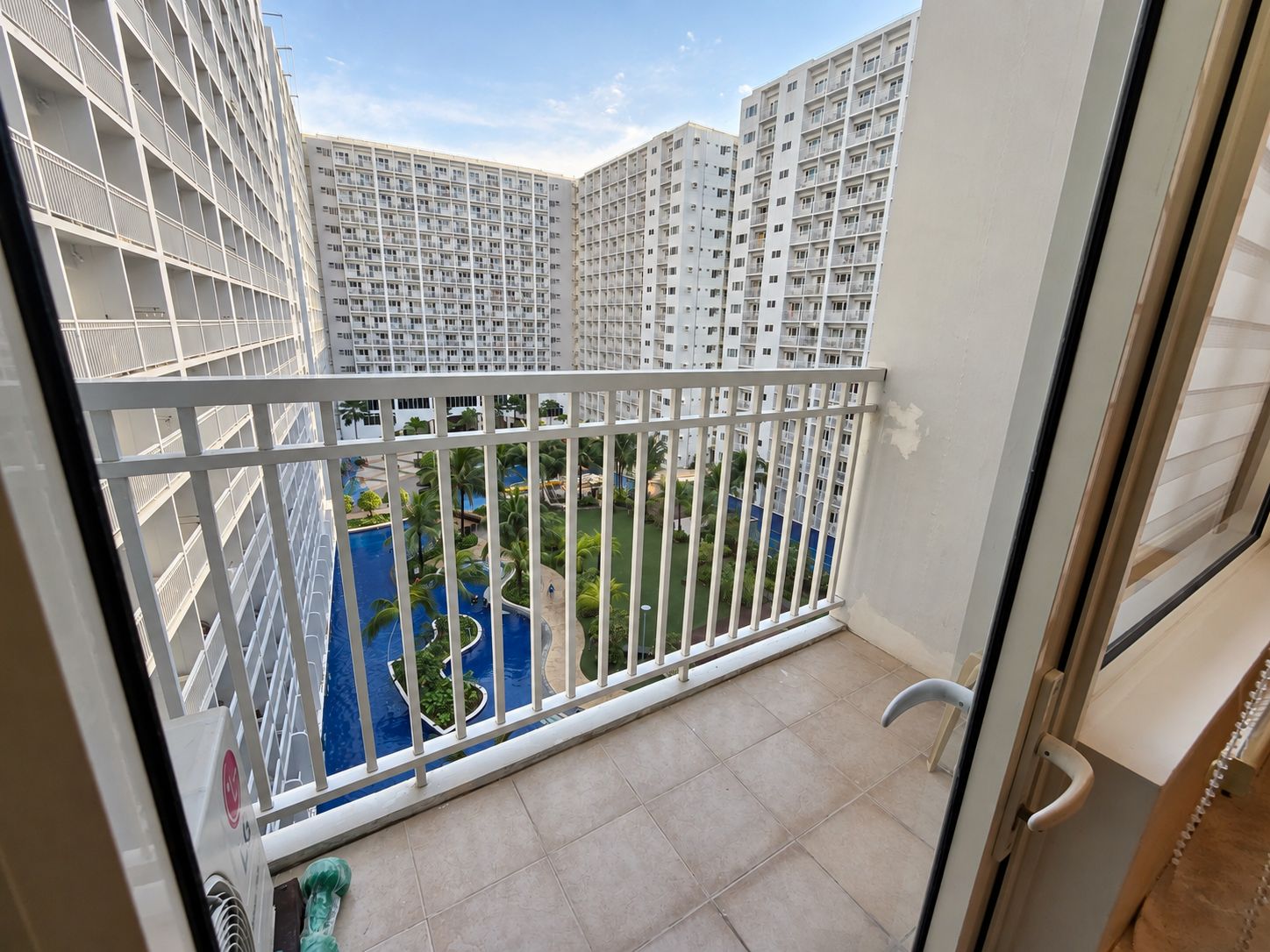 Un balcón con vista a una piscina y edificios cercanos.
