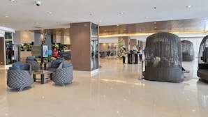 A modern lobby with seating areas, a reception desk, and a Christmas tree. - Shore 1 Residences by LUXE (Pasay City)