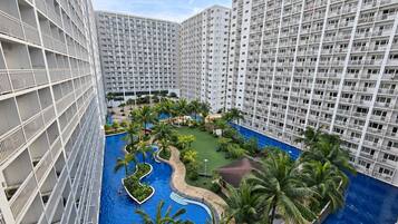 Un hôtel de grande hauteur doté de nombreux balcons, d’une piscine centrale et entouré de verdure.