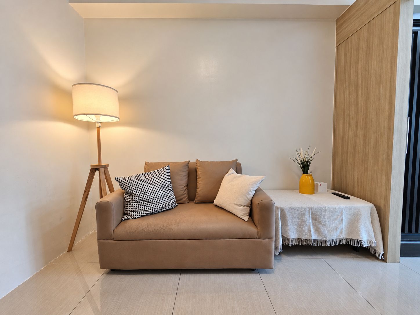 Un salon moderne avec un canapé, une lampe sur pied et une petite table sur laquelle est posé un vase.