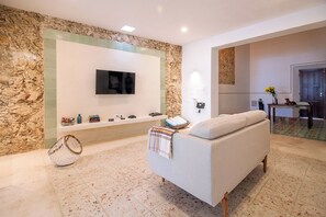 Ein modernes Wohnzimmer mit Steinwand, Flachbildfernseher, einer Couch und einem kleinen Tisch mit Dekoration.
