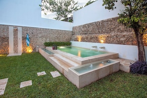 A spa area with a hot tub, stone walls, and a small garden. - Ka'an Boutique Colonial Home (Mérida)