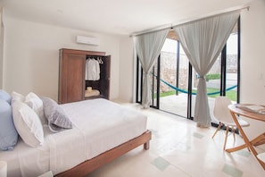 A bedroom with a bed, a wardrobe, a table with magazines, and a view of the outdoors. - Ka'an Boutique Colonial Home (Mérida)