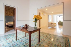 Ein Zimmer mit einem Holztisch, einer Vase mit gelben Blumen und einem gemusterten Boden.