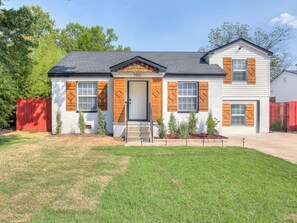 A two-story house with a front porch, a garage, and a well-maintained lawn. - Cozy 4-bed retreat. Blocks from OU. Family-friendly with yard games and firepit! (Norman)