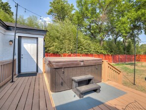 A wooden deck with a hot tub, a door, and a fence. - Cozy 4-bed retreat. Blocks from OU. Family-friendly with yard games and firepit! (Norman)