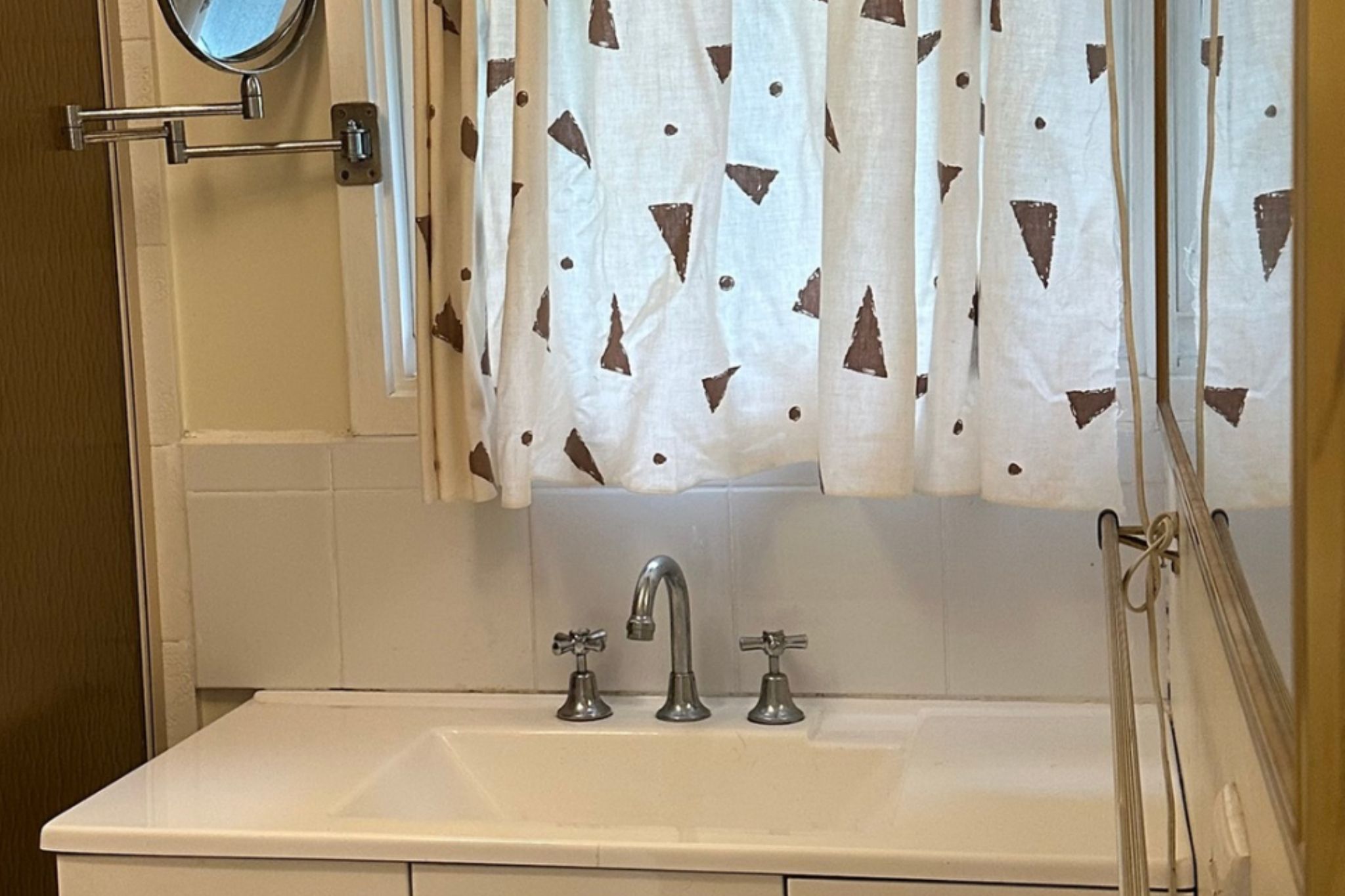 A bathroom with a white sink, two faucets, and a mirror above it.