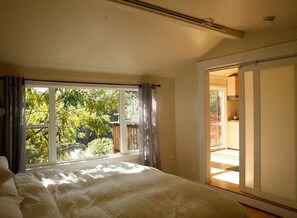 A bedroom with a large bed, a window with curtains, and a view of greenery outside. - Scandinavian Japanese Inspired Modern Sunny Private Home Nestled in Nature (Santa Cruz)