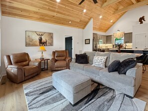 A modern living room with leather sofas, a grey sectional, and a patterned rug. - Blue Ridge Serenity - Creekside | Hot Tub | Firepit | Wildlife Galore! (Morganton)