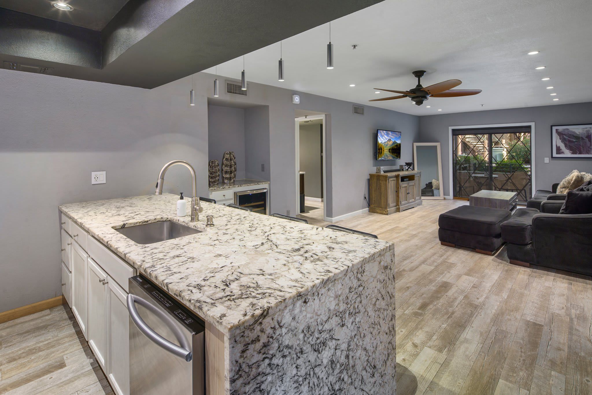 A modern kitchen with a granite countertop, built-in dishwasher, and a ceiling fan.