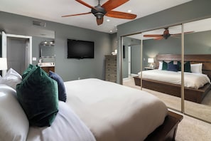 A hotel room with a large bed, a flat-screen TV, a dresser, a mirror, and a ceiling fan. - Old Town Scottsdale Oasis&Heated Pools&Golf&Gym (Scottsdale)