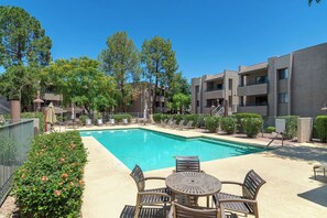 A pool area with a rectangular pool, lounge chairs, and a table with chairs. - Old Town Scottsdale Oasis&Heated Pools&Golf&Gym (Scottsdale)