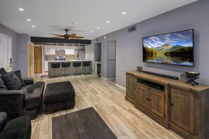 Una sala de estar moderna con un televisor de pantalla plana grande, un mueble de madera para entretenimiento y una zona de estar acogedora con chimenea.