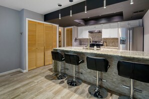 A modern kitchen with a central island, bar stools, and a wooden closet. - Old Town Scottsdale Oasis&Heated Pools&Golf&Gym (Scottsdale)