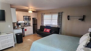 A compact room with a bed, a sofa, a small kitchenette, and a TV. - Naples Inn & Docks (Naples)