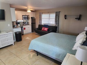 A compact room with a bed, a sofa, a small kitchenette, and a TV. - Naples Inn & Docks (Naples)