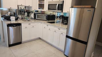 A modern kitchen with white cabinets, stainless steel appliances, and a built-in microwave.