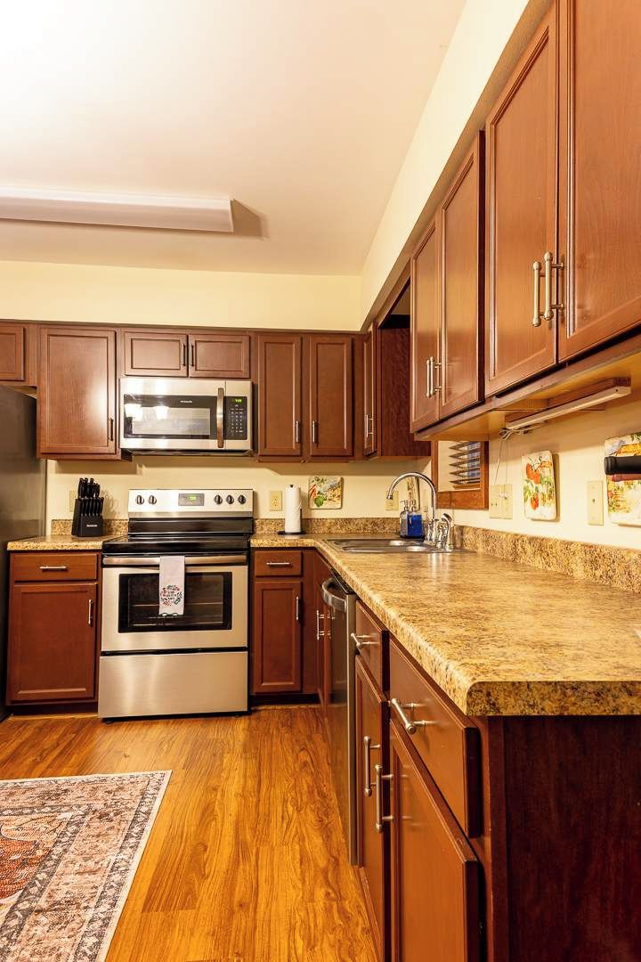 A kitchen with wooden cabinets, a stainless steel microwave, an oven, and a granite countertop.