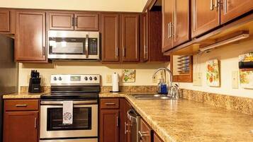 A kitchen with wooden cabinets, a stainless steel microwave, an oven, and a granite countertop.