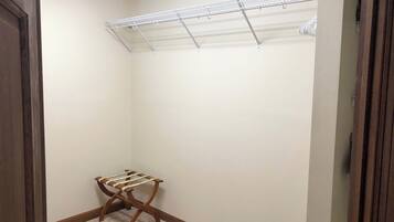 A walk-in closet with a metal drying rack, a wooden drying rack, and a carpeted floor.