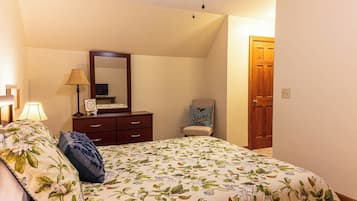 Un dormitorio con cama, cómoda, silla, lámpara, espejo y puerta.