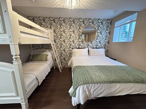 Ein Zimmer mit Etagenbetten, einem großen Spiegel und einem Fenster mit Jalousien.